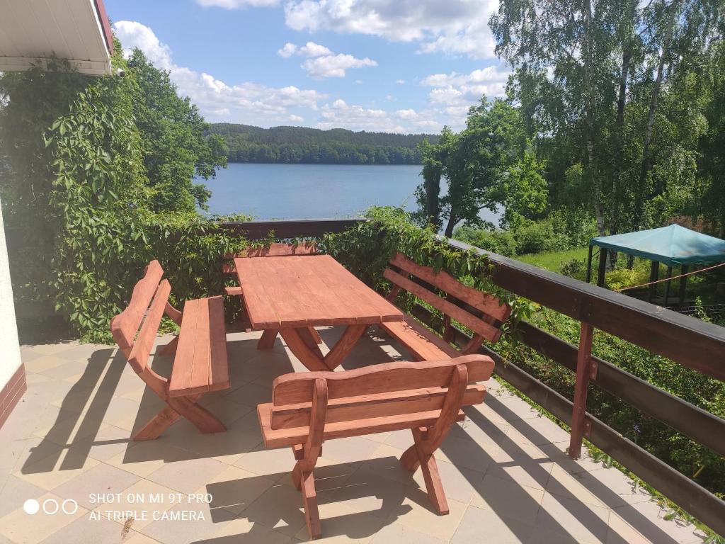 een picknicktafel en 2 stoelen op een balkon met een meer bij Villa Radunia in Borzestowska Huta