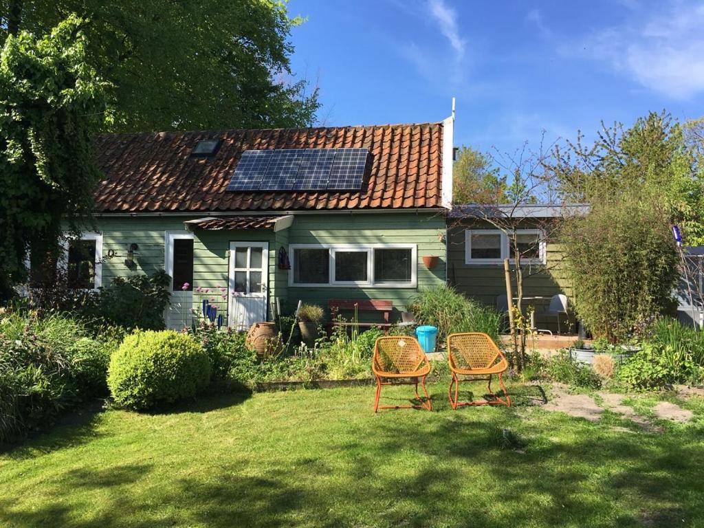 einen Hof mit zwei Stühlen und ein Haus mit einem Solardach in der Unterkunft Beemster Tiny House in Zuidoostbeemster