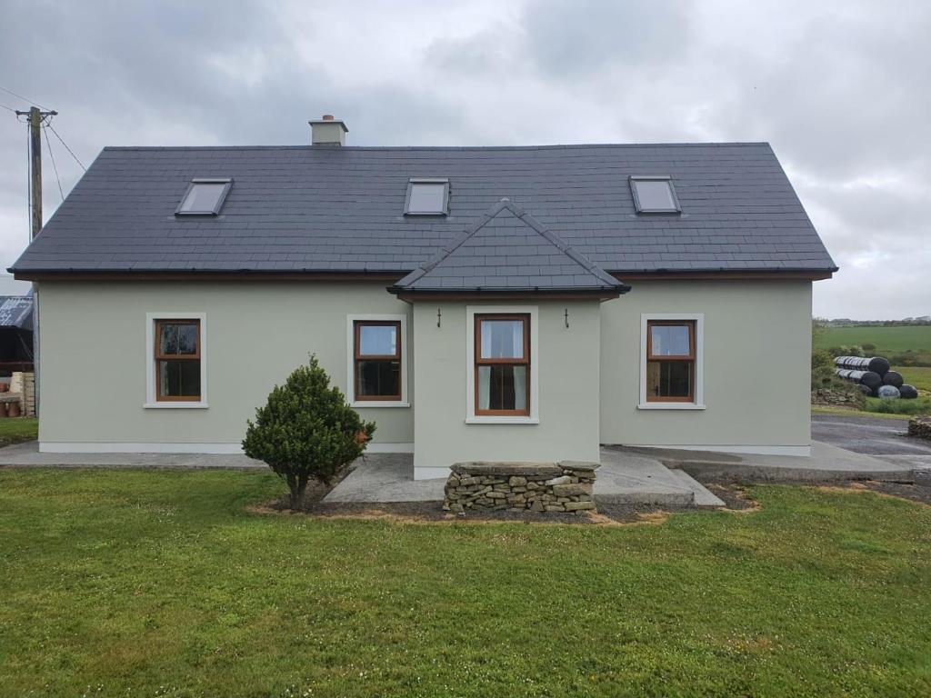 una casa blanca con techo negro en Murphys Irish Farmhouse en Tralee