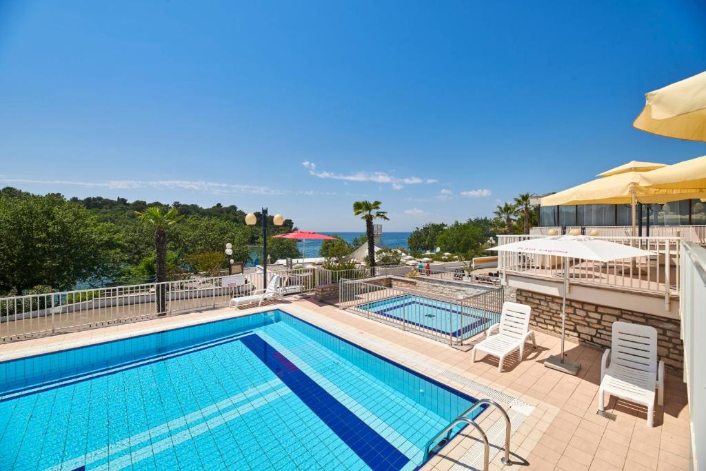 a pool with chairs and umbrellas at a resort at Hotel Zorna Plava Laguna in Poreč