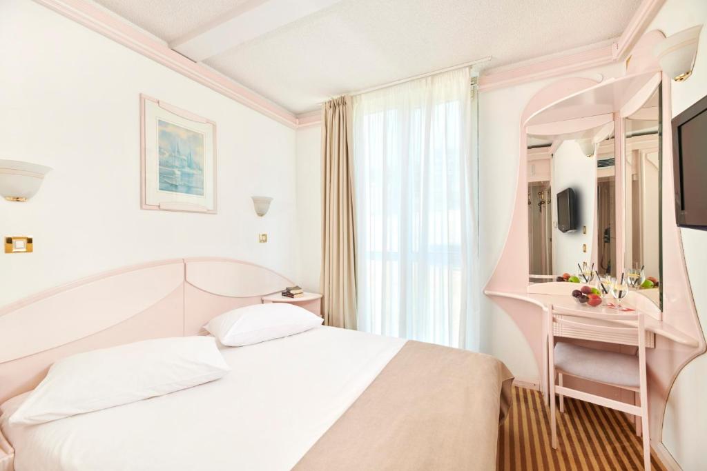 a white bedroom with a bed and a mirror at Hotel Zorna Plava Laguna in Poreč