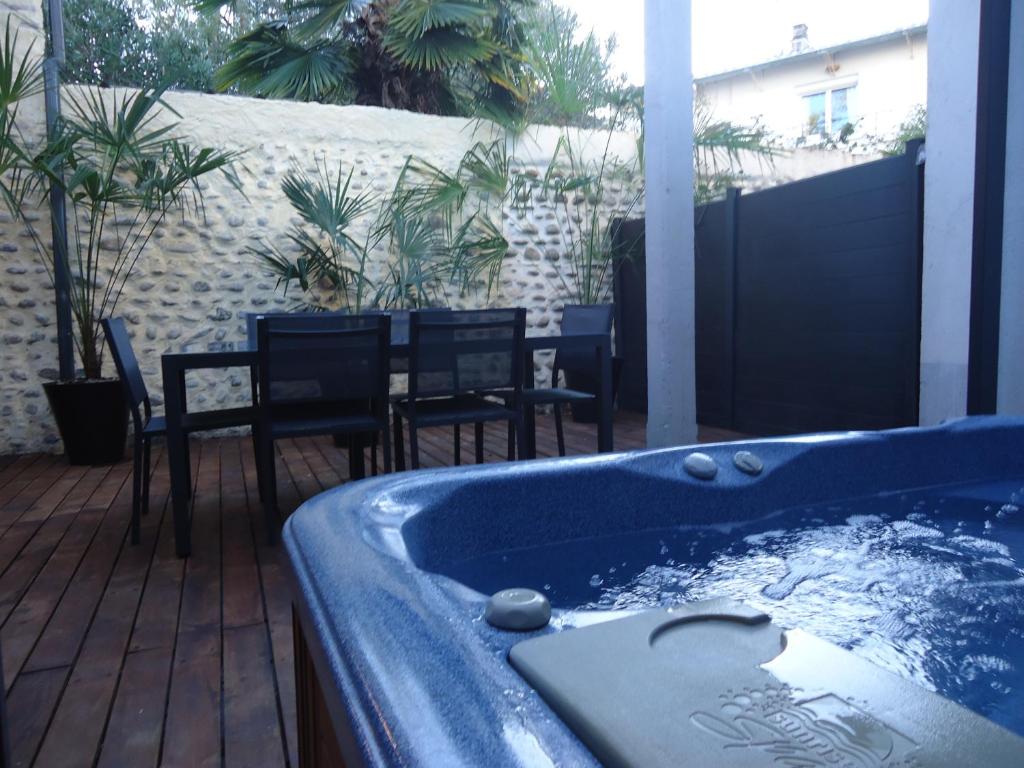 einen Whirlpool auf einer Terrasse mit Stühlen und einem Tisch in der Unterkunft Les spas de la Chartreuse in Tarbes