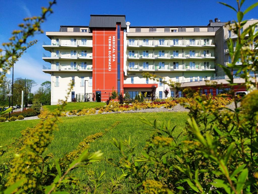 ein Hotel mit einem roten Gebäude im Hintergrund in der Unterkunft Terma Słowacki Resort Medical Spa in Busko-Zdrój