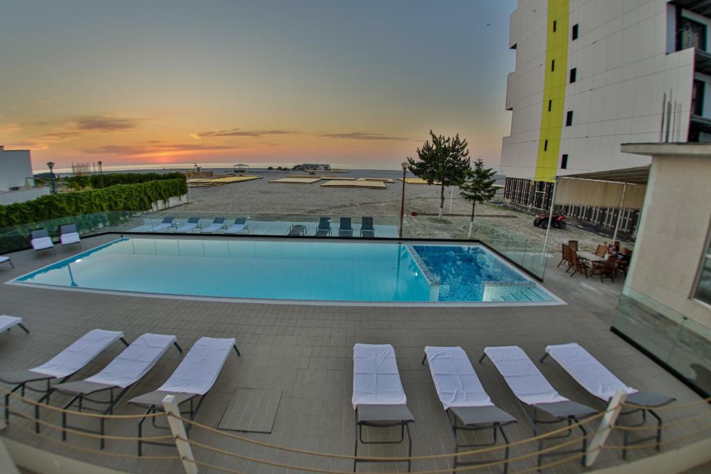 a swimming pool with lounge chairs next to a building at Jijo's Hotel in Mamaia