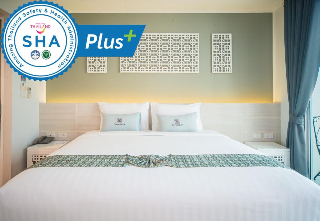 a white bed with a sign that says shha plus at Peranakan Boutique Hotel - SHA Plus in Phuket