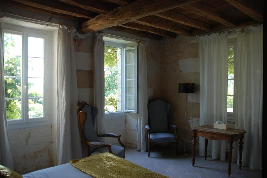 a bedroom with two chairs and a table and windows at Champ Fleuri in Angoulême