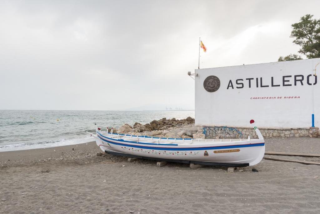 um barco sentado na praia junto ao oceano em Apartments-OILAN11 - Estudios en primera línea de playa PEDREGALEJO em Málaga