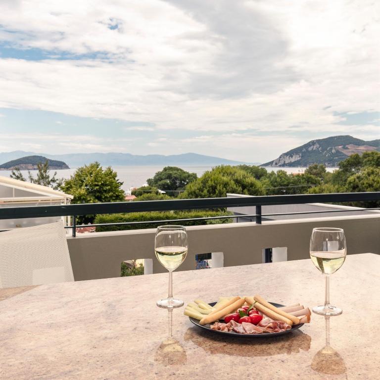 a plate of food and two glasses of wine on a table at Cove Suites Apartment in Iraklitsa