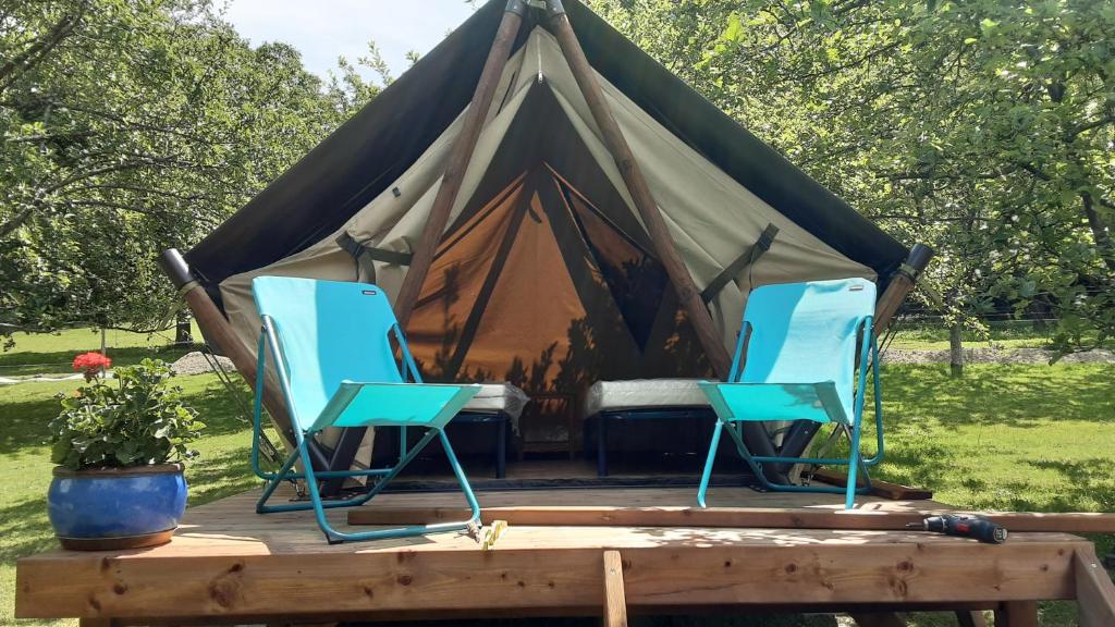 dwa niebieskie krzesła i namiot na polu w obiekcie LODGE EXTERIEUR 2 PERSONNES (possibilité toile de tente en plus pour efants avec futon) w mieście Saint-Aubin-sur-Gaillon