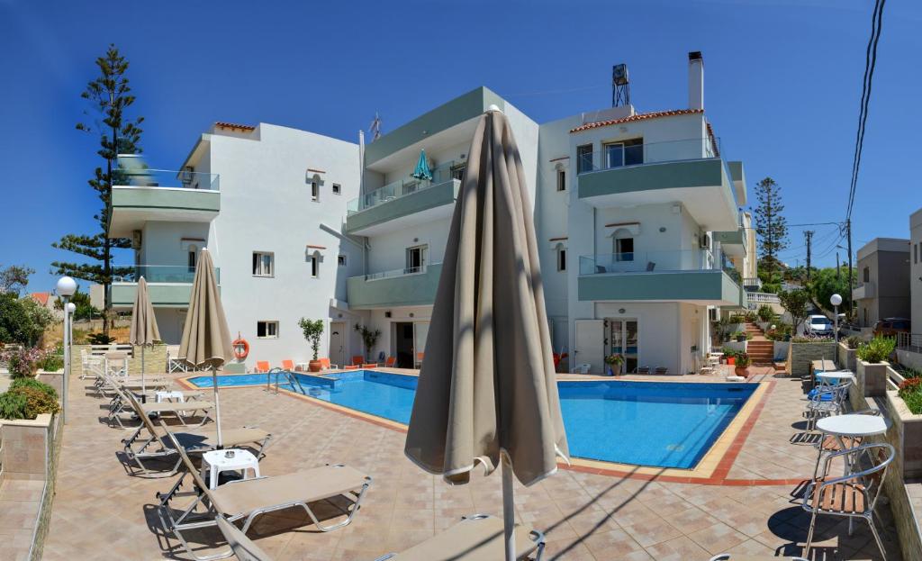 a hotel with a swimming pool with chairs and an umbrella at Sofia Apartments in Kalamaki Chanion
