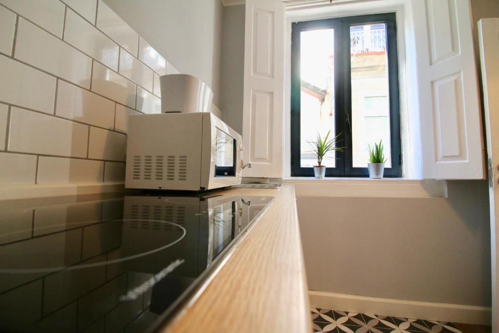 een keuken met een magnetron en een raam bij D&S - Lapa 32 in Porto