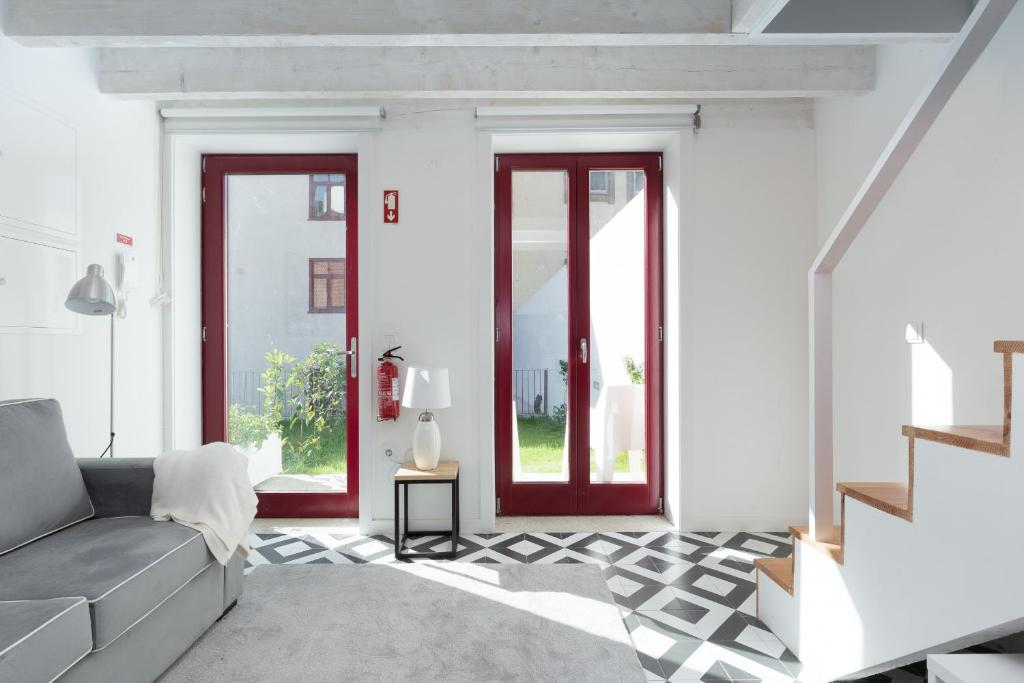 una sala de estar con paredes blancas y puertas rojas en Loureiro Villas, en Oporto