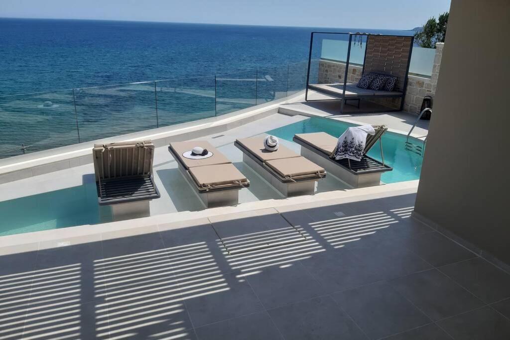 a balcony with a table and chairs and the ocean at Luxury Villa Dioskouroi eco pool & jacuzzi Kalyves in Kalyves