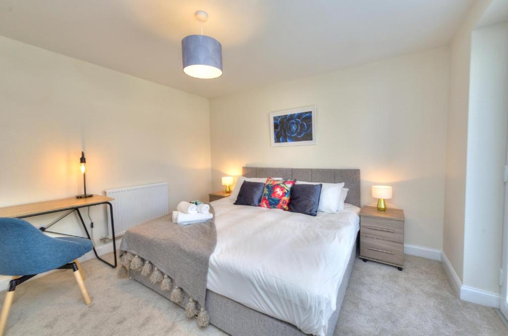 a bedroom with a bed and a desk and a chair at Executive Fairfields Apartment by PAY AS U STAY in Milton Keynes