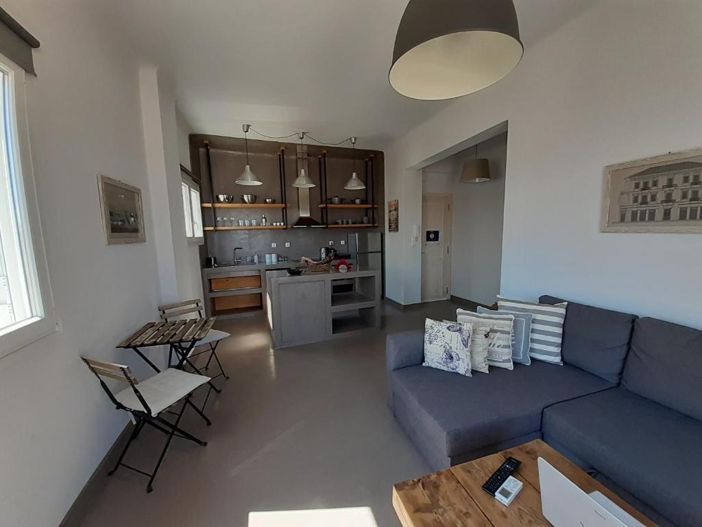 a living room with a blue couch and a kitchen at Plakes Luxury Apartments in Ermoupoli