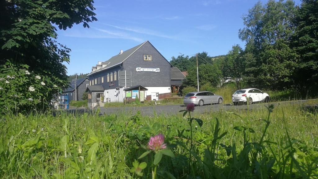 uma casa com dois carros estacionados em frente em Gasthaus & Pension Am Rennsteig em Spechtsbrunn