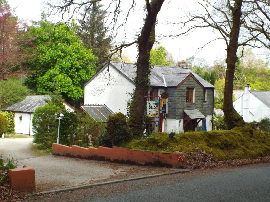 a small white house with a tree in front of it at Woodpeckers in North Hill