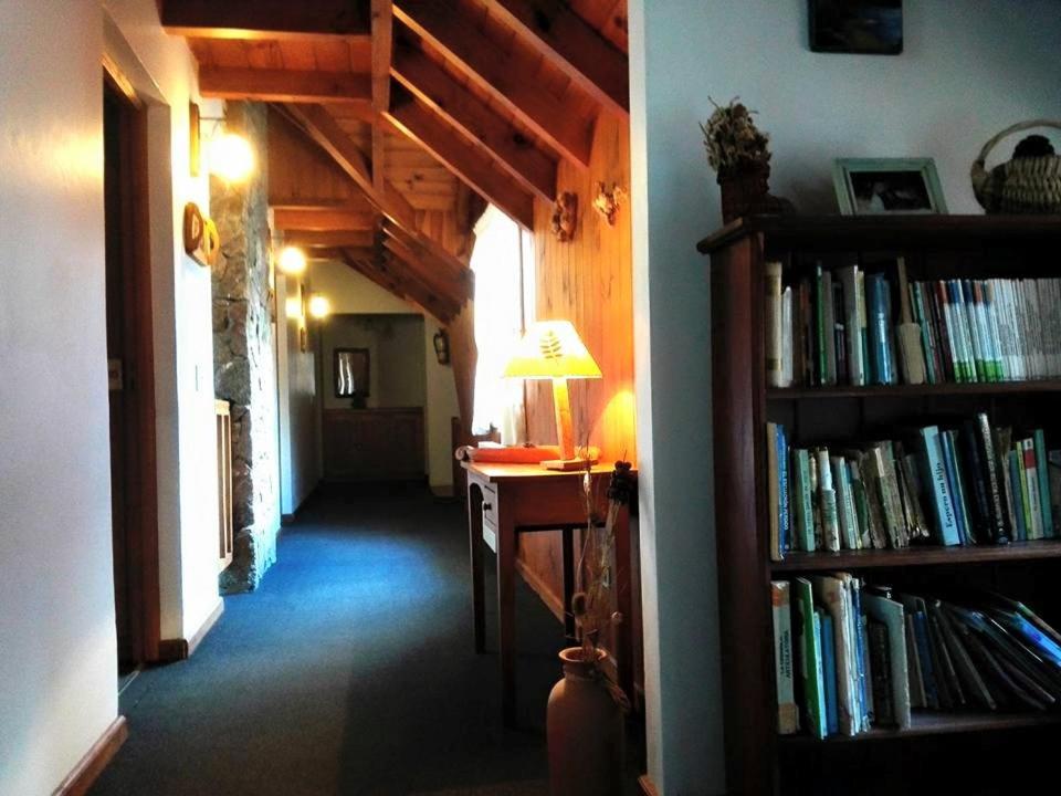 a hallway with a desk and a book shelf filled with books at Hosteria y Cabañas Posada Quinen in San Martín de los Andes