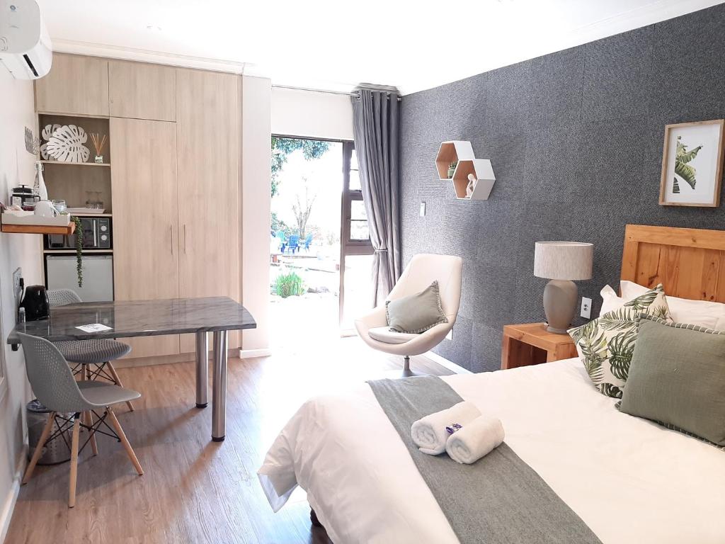 1 dormitorio con 1 cama, mesa y sillas en The Hillcrest Guesthouse, en East London