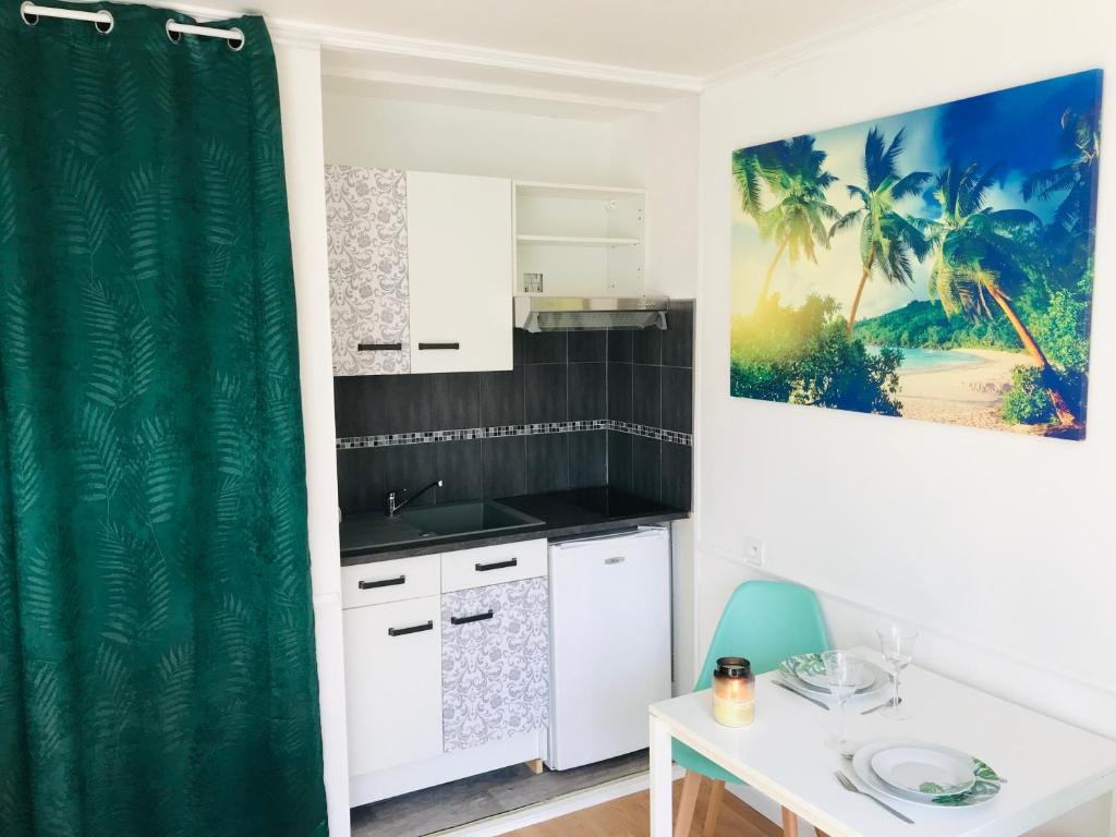 a kitchen with white cabinets and a green shower curtain at LE COSY - Lumineux - Proche de Rennes - Spacieux in Liffré