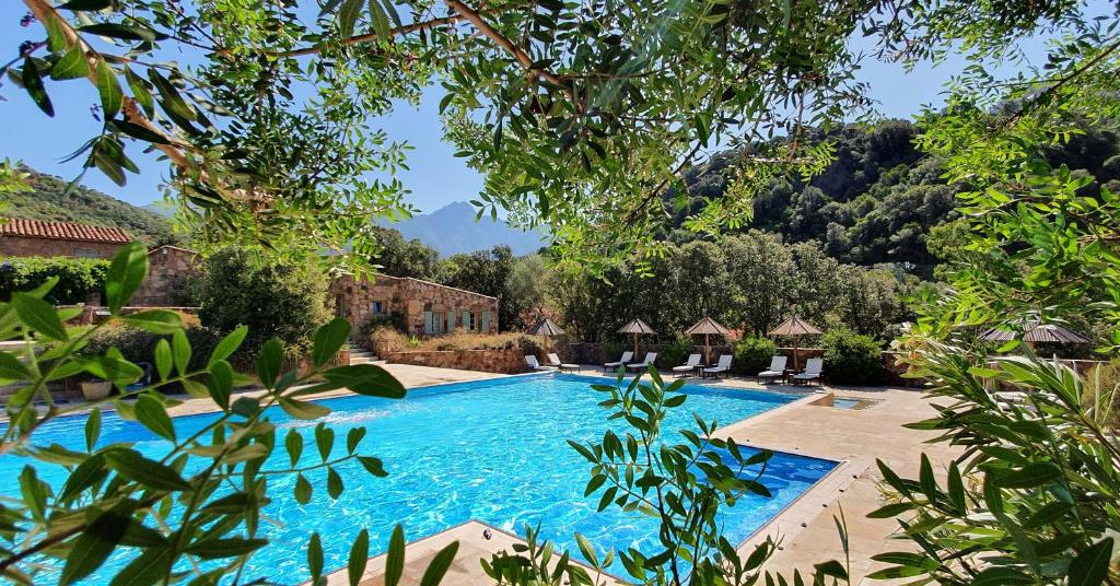 uma piscina num resort com montanhas ao fundo em Domaine Codaleone em Serriera