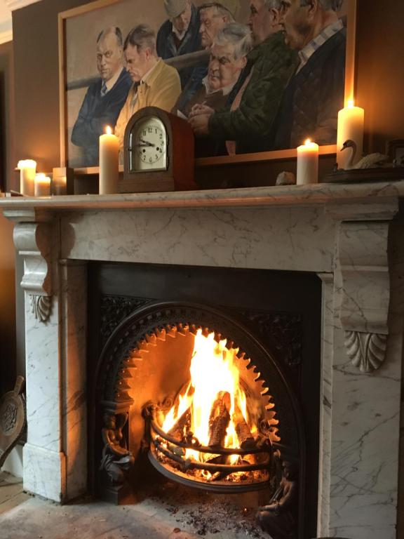 a fireplace with a fire in it with candles at Kings B&B in South Molton