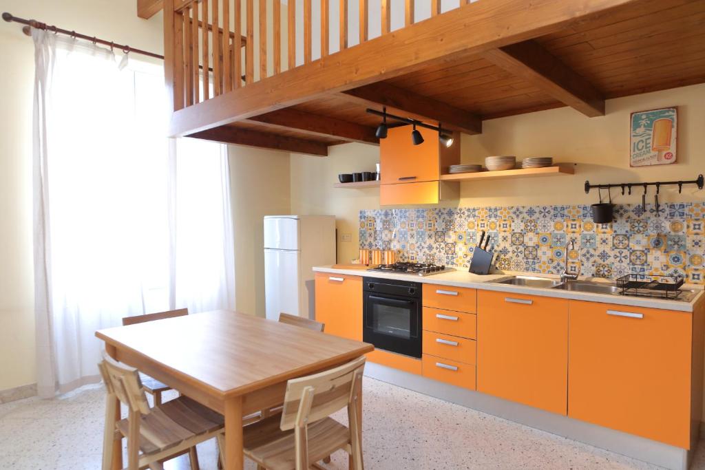 a kitchen with orange cabinets and a wooden table at Sunny Flat - SELF Apartments in Cefalù