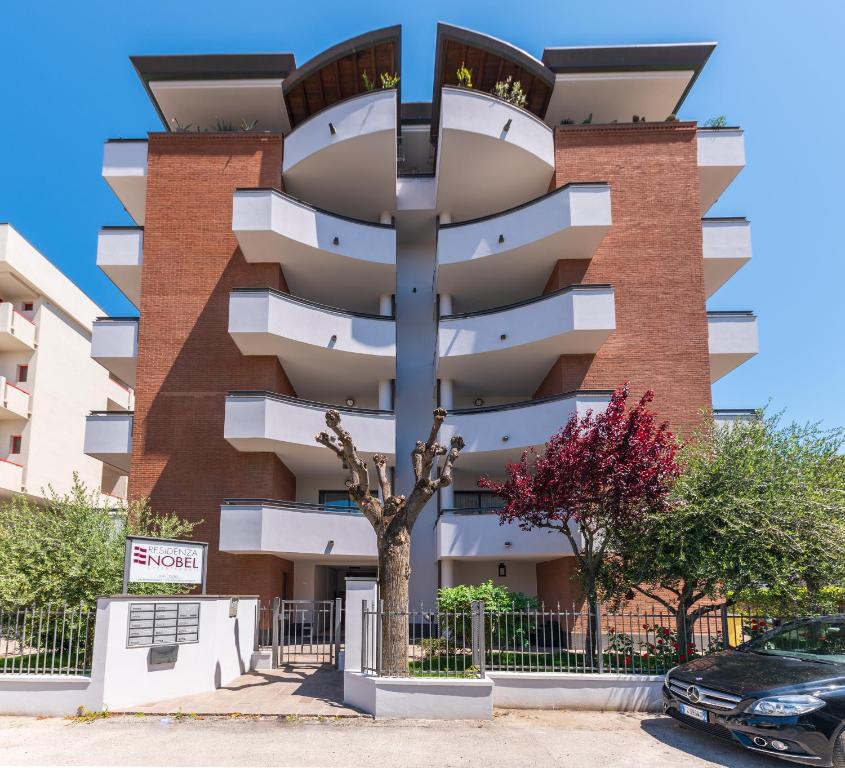 a building with a tree in front of it at Residenza Nobel Appartamenti in Rimini