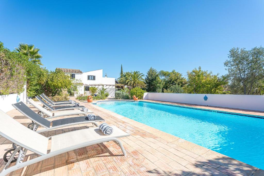 a swimming pool with lounge chairs next to a house at Quinta da Alfazema in Quelfes
