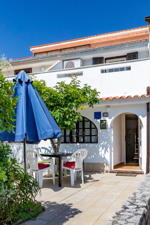 a patio with a table and a blue umbrella at Apartmani Nadia in Punat