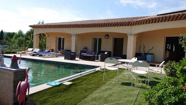 una casa con piscina y sillas en el patio en Villa Les Marmottes, en Le Luc