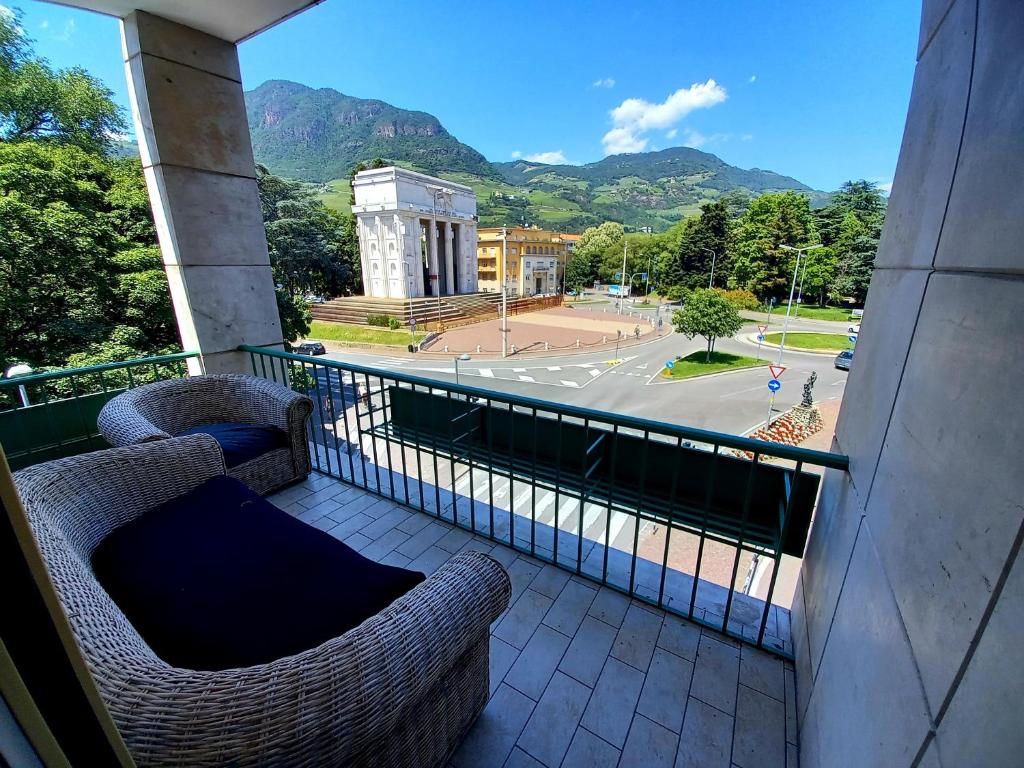 balcón con 2 sillas y vistas a la calle en Alps Apartments Viktory, en Bolzano