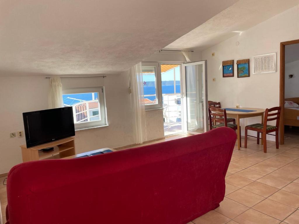 un salon avec un canapé rouge et une télévision dans l'établissement Apartments Papic, à Trogir