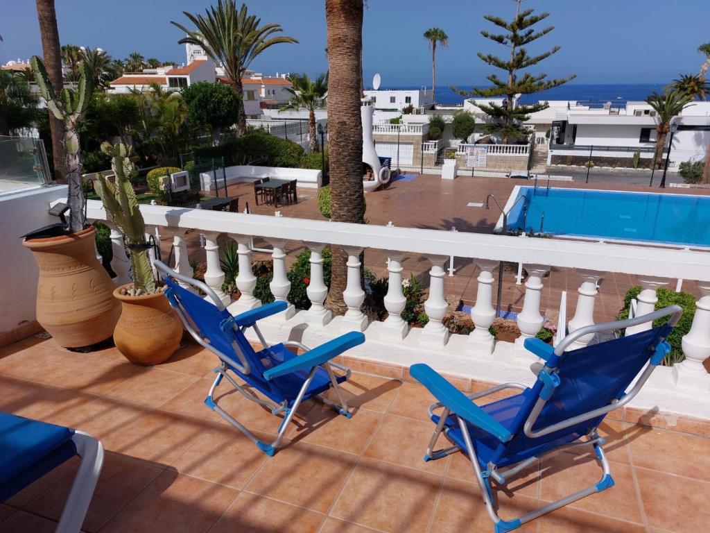 Duas cadeiras azuis numa varanda com piscina em FIRST LINE Villa Floor Apartment with amazing sea view Air Conditioned just 50m from the beach em Adeje