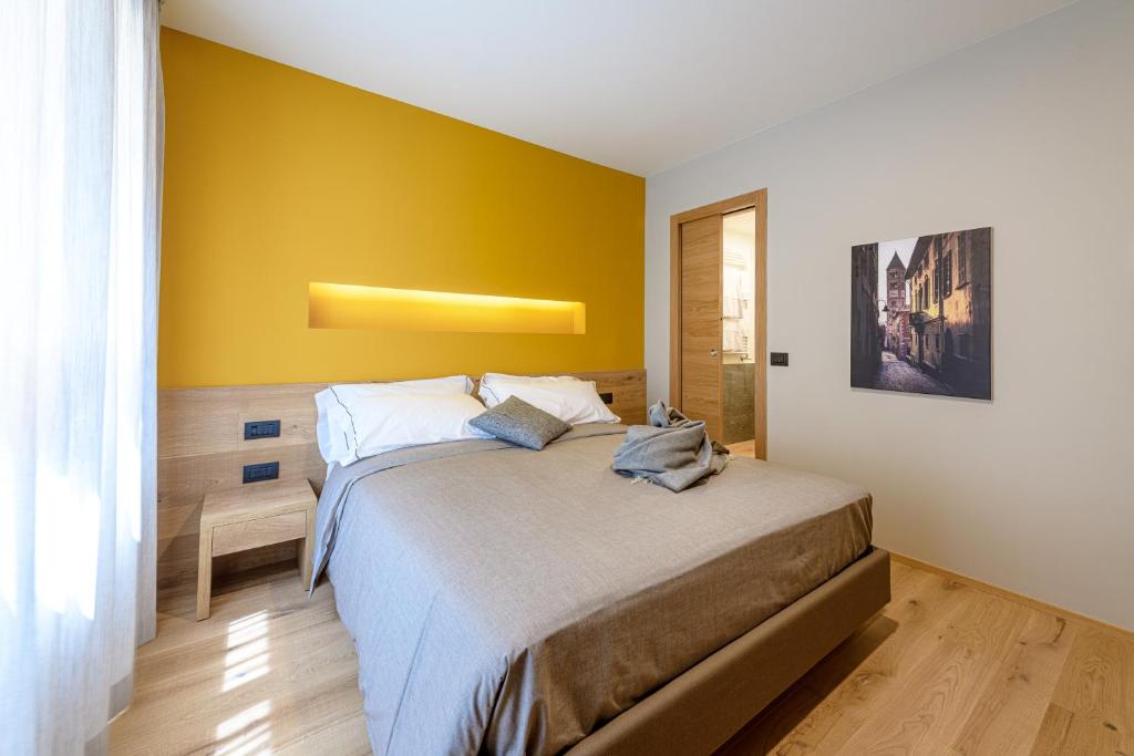 een slaapkamer met een bed met een gele muur bij SANMARTINO SUITE in Tirano