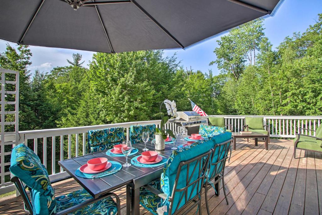 a table and chairs on a deck with an umbrella at North Conway Home with Access to 5 Private Beaches! in Conway