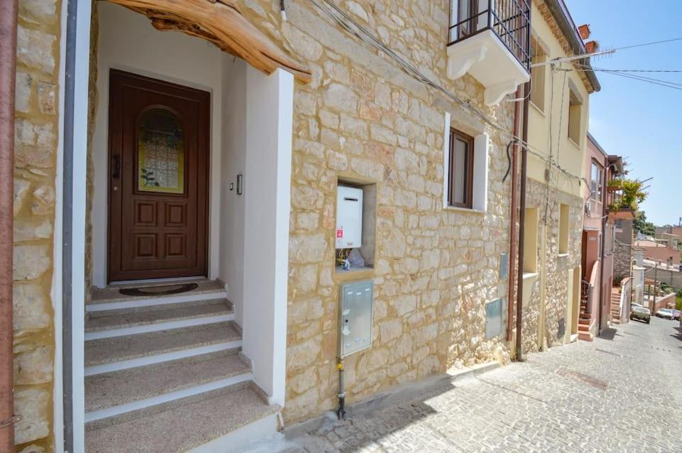 un edificio de ladrillo con una puerta y escaleras en una calle en Appartamento vista incantevole Domm'e Orrosaria, en Baunei