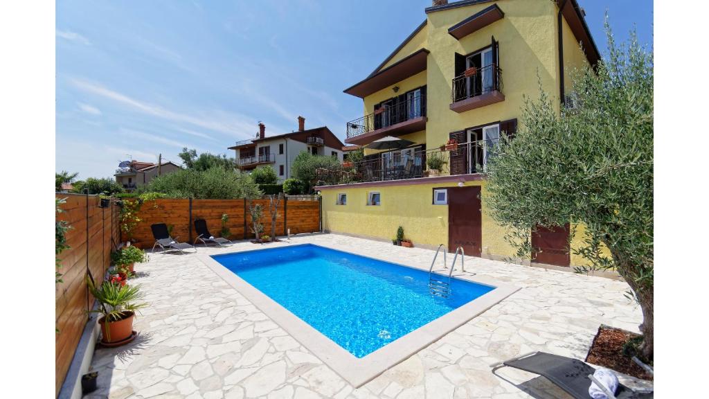 a swimming pool in front of a house at Holiday Home Vlady in Buje