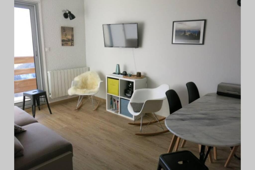 sala de estar con mesa, sillas y TV en Saint-Lary-Soulan 1700, calme, ski, vtt et rando, en Saint-Lary-Soulan