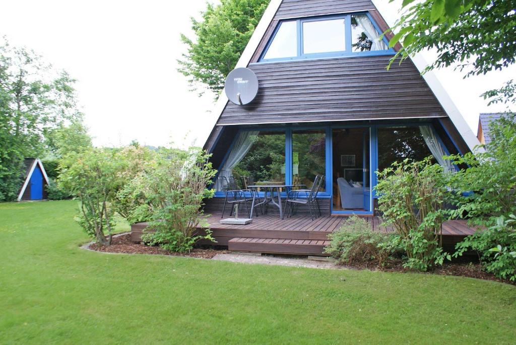 uma pequena casa com um deque de madeira com uma mesa em Zeltdachhaus mit WLAN und grosser Terrasse em Damp