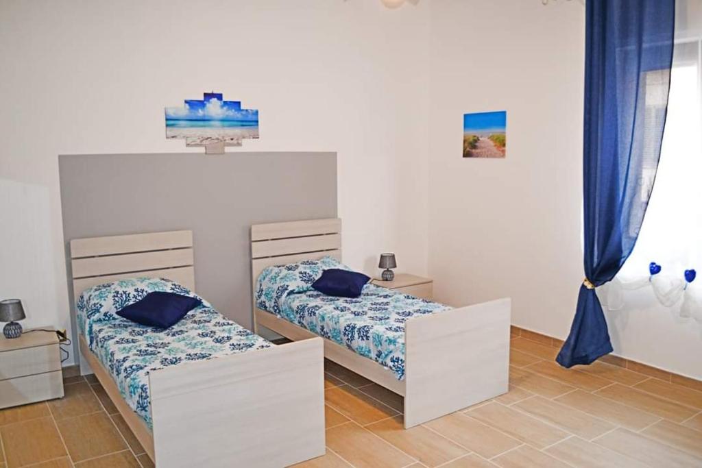 two beds in a room with blue curtains at TERESA HOLIDAY in Sarroch