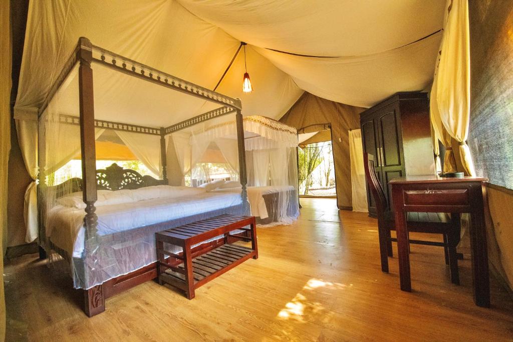 ein Schlafzimmer mit einem Himmelbett in einem Zelt in der Unterkunft Lorian safari camp limited in Narok