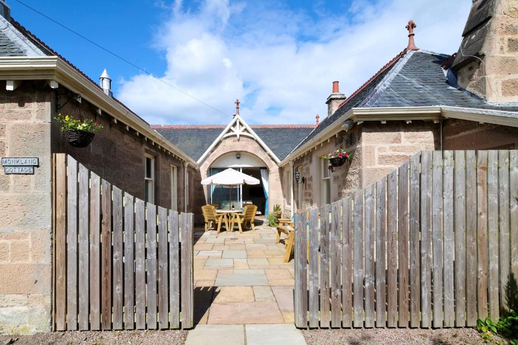 a wooden fence in front of a house with a patio at Monkland Cottage in Nairn