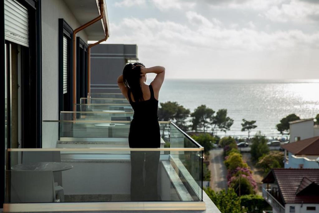 een vrouw op een balkon met uitzicht op de oceaan bij Rozafa Blu Hotel in Shëngjin