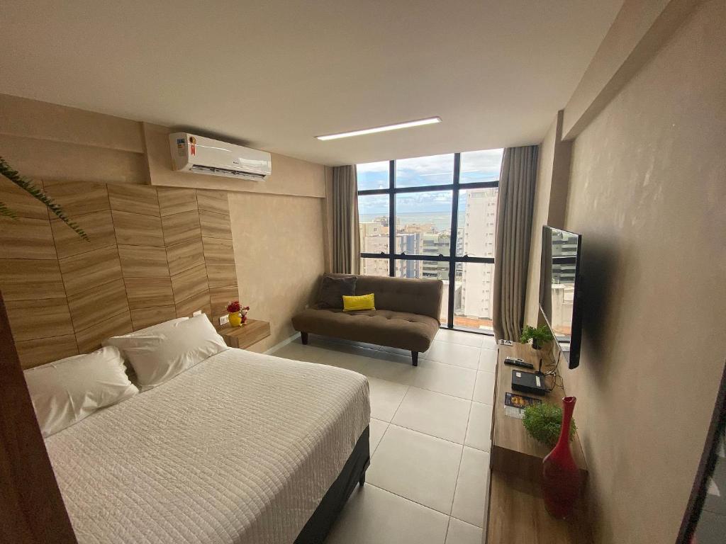 ein Schlafzimmer mit einem Bett, einem Sofa und einem TV in der Unterkunft Edifício Time Apto 1101 ER Hospedagens in Maceió