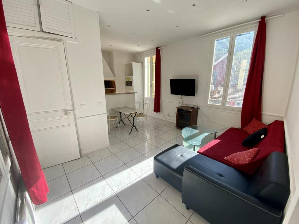 uma sala de estar com um sofá azul e uma televisão em les meublés du soleil em Menton