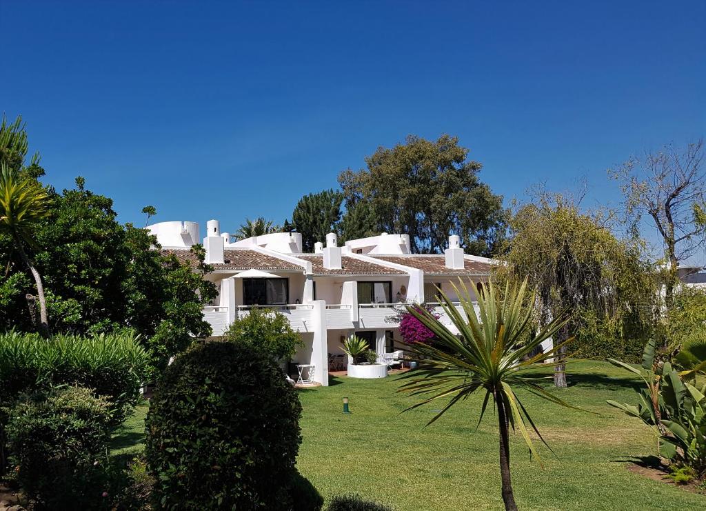 una gran casa blanca con árboles y un patio verde en Grey Heron Apartment en Quinta do Lago