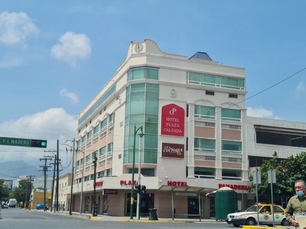モンテレイにあるHotel Plaza Calzadaの白い建物の横に赤い看板