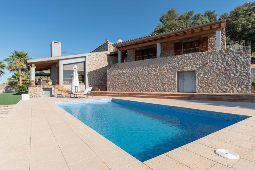une villa avec une piscine en face d'une maison dans l'établissement Es Flavo, à Sineu