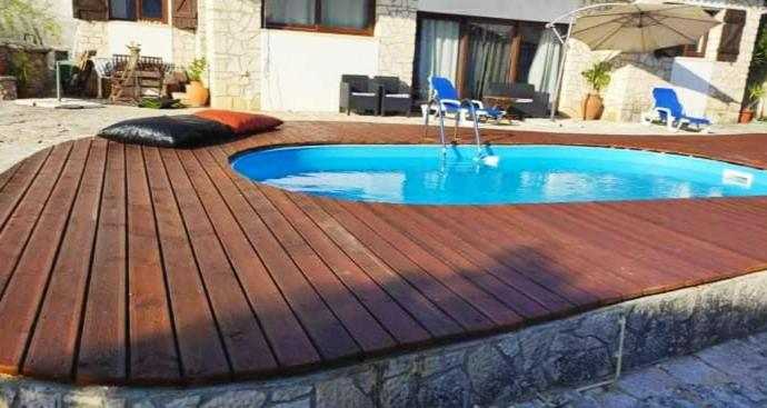 a swimming pool on a wooden deck with an umbrella at Louro's Villa - 12130AL in Cantanhede